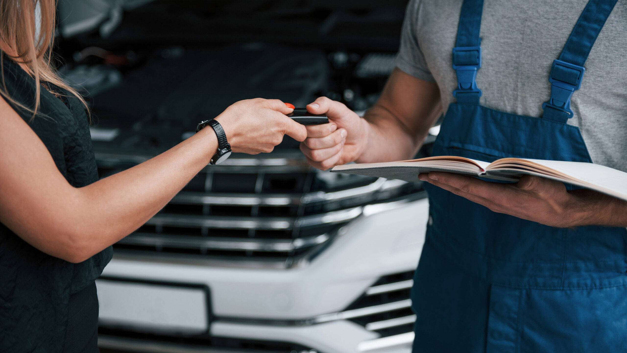 Kundin übergibt Autoschlüssel an Kfz-Mechaniker